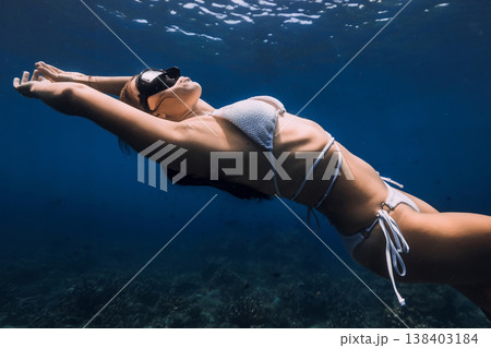 Woman free diving in white bikini underwater in clear blue ocean Woman free diving in white bikini underwater in clear blue ocean 138403184