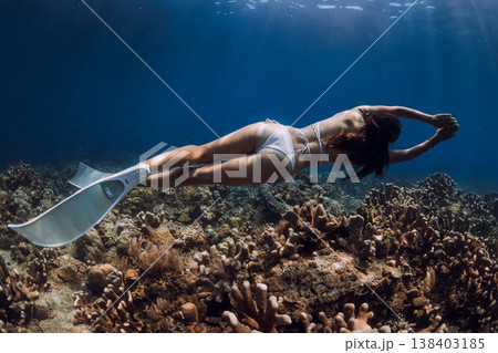 Female freediver swimming over coral reef with fins in tropical deep sea 138403185