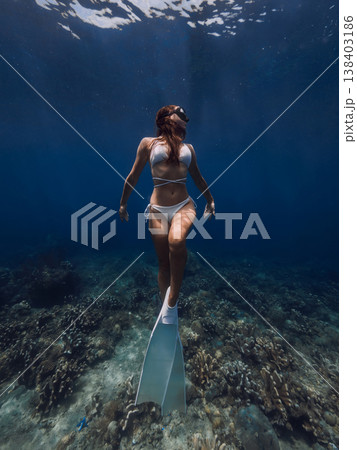 Young slim woman freediving above coral reef in deep blue ocean 138403186