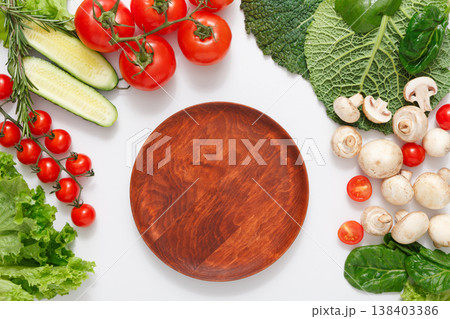 Brown wood cutting board, border of fresh organic vegetables, fruits and nuts on white background. Healthy natural food on table with copy space, top view 138403386