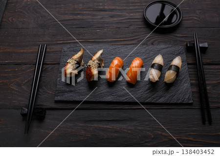 Colorful sushi and rolls platter in japanese restaurant, with chopsticks and soy sauce on dark background Colorful sushi and rolls platter in japanese restaurant, with chopsticks and soy sauce on dark background 138403452