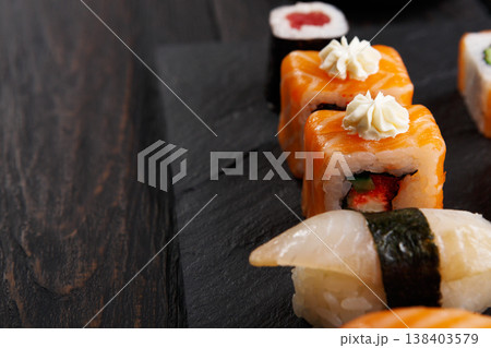 Sushi plate. Japanese food restaurant, unagi and salmon rolls closeup on dark background. Pov with copy space on black wood Sushi plate. Japanese food restaurant, unagi and salmon rolls closeup on dark background. Pov with copy space on black wood 138403579