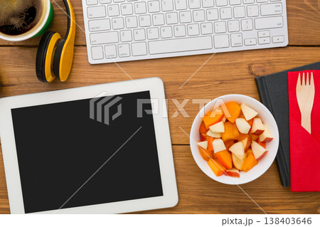 Healthy lunch at workplace with copy space on tablet pc. Top view flat lay of desktop fruit salad in foil container and mobile phone on wooden desk background 138403646