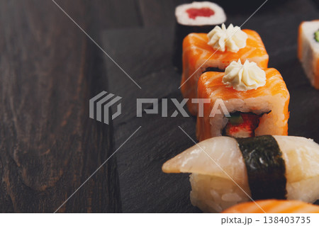 Sushi plate. Japanese food restaurant, unagi and salmon rolls closeup on dark background. Pov with copy space on black wood 138403735