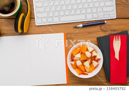 Healthy lunch at workplace. Top view with copy space, flat lay of desktop fruit snack in foil container on wooden desk background 138403782