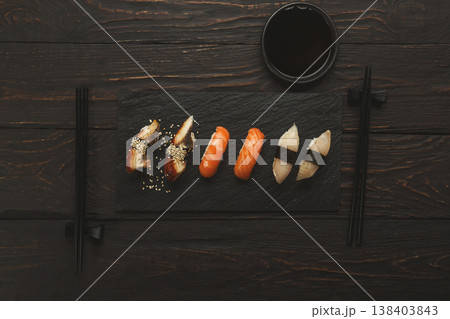 Colorful sushi platter in japanese restaurant, with chopsticks and soy sauce on dark wooden background, top view, flat lay, copy space 138403843