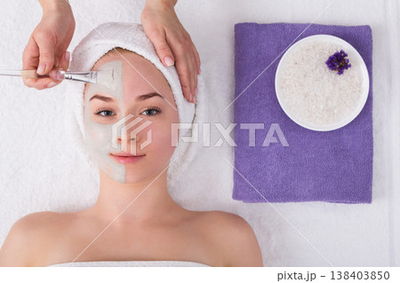Face mask apply, spa beauty treatment, skincare. Woman getting facial care by beautician at spa salon, top view 138403850