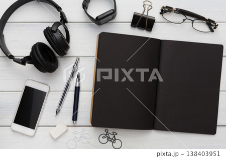 Education, office and work concept, top view of black and white workplace. Stationery supplies - blank notepad, pens, binder clips, phone, watch on wooden desktop, flat lay, copy space, template 138403951