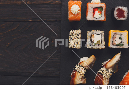 Sushi plate. Japanese food restaurant, unagi and salmon rolls on dark background. Top view with copy space on black wood 138403995