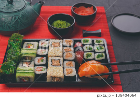 Eating salmon sushi. Japanese food restaurant, sushi maki and roll plate or platter set. Closeup of hand with chopsticks taking roll. Eating salmon sushi. Japanese food restaurant, sushi maki and roll plate or platter set. Closeup of hand with chopsticks taking roll. 138404064