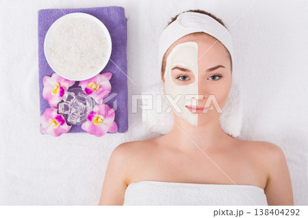 Face mask, spa beauty treatment. Woman applying facial clay mask at spa salon, skincare, top view, overhead Face mask, spa beauty treatment. Woman applying facial clay mask at spa salon, skincare, top view, overhead 138404292