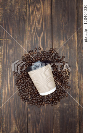 Mockup coffee in a disposable cup on a wooden table and a coffee grains, dark background. Top view 138404336
