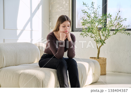 Unhappy upset stressed young woman sitting on sofa at home Unhappy upset stressed young woman sitting on sofa at home 138404387