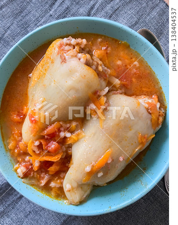 Cabbage rolls filled with meat and grains sit in a blue bowl. The dish is covered in a rich tomato sauce. It is ready to be enjoyed at dinner time in a warm kitchen Cabbage rolls filled with meat and grains sit in a blue bowl. The dish is covered in a rich tomato sauce. It is ready to be enjoyed at dinner time in a warm kitchen 138404537