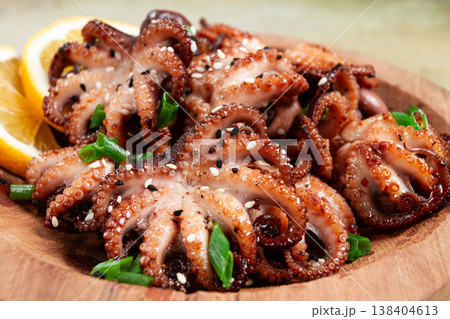 grilled baby octopus with green onions, lemon slices, on a wooden plate, homemade, no people, 138404613