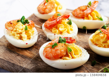 Boiled eggs stuffed with yolk and seasoned with mayonnaise, stuffed eggs with shrimp, on a wooden chopping board, selective focus, close-up, no people, Boiled eggs stuffed with yolk and seasoned with mayonnaise, stuffed eggs with shrimp, on a wooden chopping board, selective focus, close-up, no people, 138404638