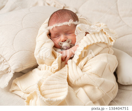 Peaceful newborn baby sleeping in a cozy knitted blanket. Soft natural light, neutral tones and minimalist composition highlighting innocence, warmth and family care 138404751