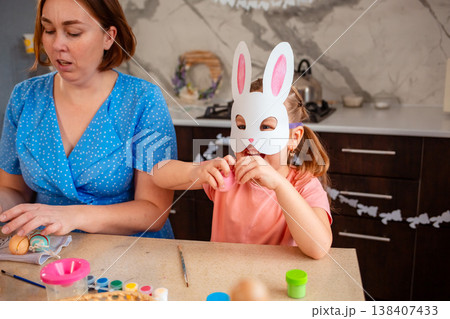 Caucasian mother and daughter preparing for Easter by coloring eggs, building memories and spending meaningful time. Concept of family traditions, childhood and festive preparation. Mid shot Caucasian mother and daughter preparing for Easter by coloring eggs, building memories and spending meaningful time. Concept of family traditions, childhood and festive preparation. Mid shot 138407433