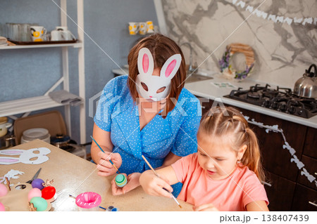 A cozy Caucasian family prepares for Easter by decorating paper masks together indoors. A cozy Caucasian family prepares for Easter by decorating paper masks together indoors. 138407439