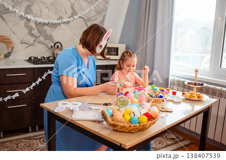 A cheerful Caucasian family lifestyle moment as a mother and daughter paint festive paper masks. 138407539
