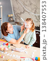 A beautiful family moment as a mother and her daughter wear Easter bunny masks at home, enjoying playful crafting time before the holiday celebration. Vertical 138407553