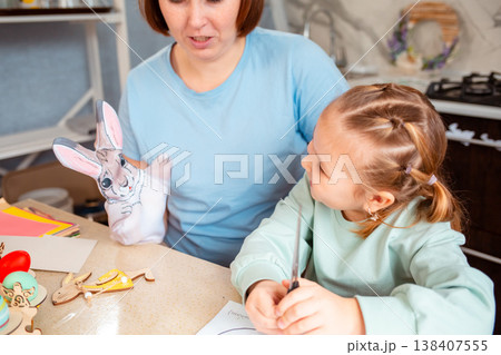 A cozy Caucasian family prepares for Easter by crafting and cutting decorations at the table indoors. Mid shot 138407555