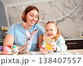 A smiling young Caucasian woman and her daughter create festive bunny masks while preparing for the spring holiday. Low angle view 138407557