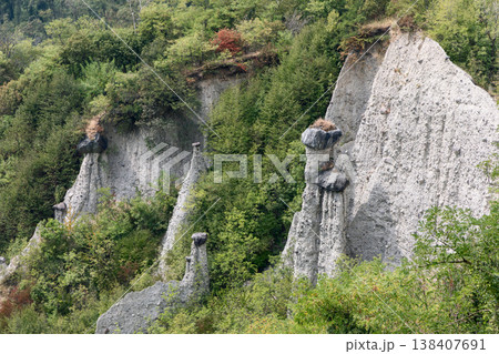 Stone capped earth columns at the Pyramids of Zone rise near Lake Iseo with white spires Stone capped earth columns at the Pyramids of Zone rise near Lake Iseo with white spires 138407691
