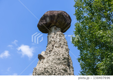 Zone Rock Pyramids in Lombardy show a giant dark capstone crowning a pale earth tower under blue sky Zone Rock Pyramids in Lombardy show a giant dark capstone crowning a pale earth tower under blue sky 138407696