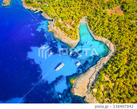 Top down aerial drone view of luxury yachts and boats in a turquoise bay with crystal clear water. 138407842