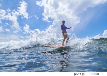Youthful Girl Skillfully Maintains Her Balance On surfboard Amidst Ocean Scenery Youthful Girl Skillfully Maintains Her Balance On surfboard Amidst Ocean Scenery 138408139