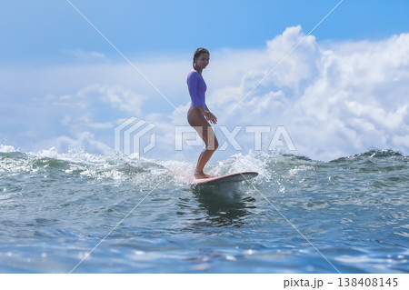 Teenage Girl Surfing Glossy Blue Crest With Bold Stances And Bright Sky Teenage Girl Surfing Glossy Blue Crest With Bold Stances And Bright Sky 138408145