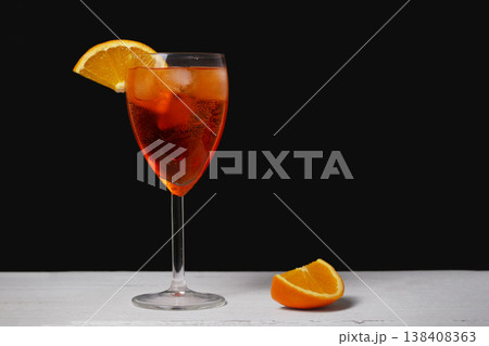 Classic Aperol Spritz with ice and fresh orange garnish in elegant glass on dark background. Refreshing summer cocktail, bar drink, Italian aperitif, minimal style Classic Aperol Spritz with ice and fresh orange garnish in elegant glass on dark background. Refreshing summer cocktail, bar drink, Italian aperitif, minimal style 138408363