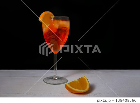 Classic Aperol Spritz with ice and fresh orange garnish in elegant glass on dark background. Refreshing summer cocktail, bar drink, Italian aperitif, minimal style Classic Aperol Spritz with ice and fresh orange garnish in elegant glass on dark background. Refreshing summer cocktail, bar drink, Italian aperitif, minimal style 138408366