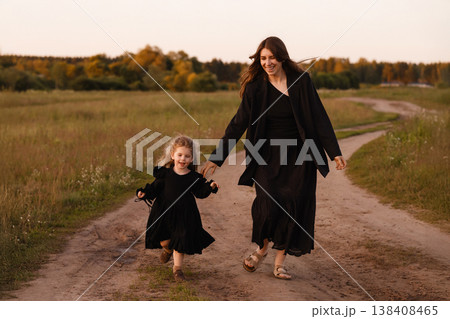Mother And Daughter Enjoying Sunset. Parent And Child Strolling Along Countryside Path Mother And Daughter Enjoying Sunset. Parent And Child Strolling Along Countryside Path 138408465