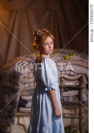 Little girl in blue dress with crown looking back near stacked mattresses, princess and the pea Little girl in blue dress with crown looking back near stacked mattresses, princess and the pea 138408479