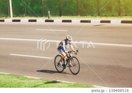 Female sportsman cyclist riding racing bicycle. Woman cycling on countryside summer road or highway. Training for triathlon or cycling competition. Female sportsman cyclist riding racing bicycle. Woman cycling on countryside summer road or highway. Training for triathlon or cycling competition. 138408518
