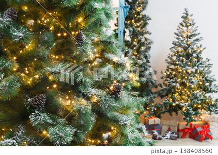 Decorated christmas trees background. Fluffy green pines in shiny garland and beautifully wrapped presents. Xmas and new year eve atmosphere, closeup, copy space Decorated christmas trees background. Fluffy green pines in shiny garland and beautifully wrapped presents. Xmas and new year eve atmosphere, closeup, copy space 138408560