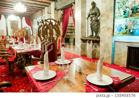 Restaurant interior styled as ancient medieval castle, palace. Red Thrones and tables. Festive british restaurant interior, catering, served banquet or wedding. Vintage, castle and palace interior. Restaurant interior styled as ancient medieval castle, palace. Red Thrones and tables. Festive british restaurant interior, catering, served banquet or wedding. Vintage, castle and palace interior. 138408576