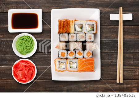 Japanese food restaurant delivery - sushi maki, unagi and roll platter set isolated on brown wood background, above view Japanese food restaurant delivery - sushi maki, unagi and roll platter set isolated on brown wood background, above view 138408615