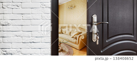 Half opened door to a living room. Door handle, door lock. Lounge door half open. Opening door. Privacy, safety concept. Entrance to the room. Door at white brick wall, modern interior design. Half opened door to a living room. Door handle, door lock. Lounge door half open. Opening door. Privacy, safety concept. Entrance to the room. Door at white brick wall, modern interior design. 138408652