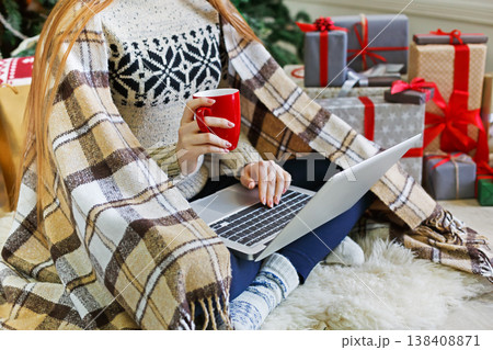 Christmas online shopping. Unrecognized woman with coffee, buy presents on laptop, prepare to xmas, among gift boxes and packages. Winter sales Christmas online shopping. Unrecognized woman with coffee, buy presents on laptop, prepare to xmas, among gift boxes and packages. Winter sales 138408871
