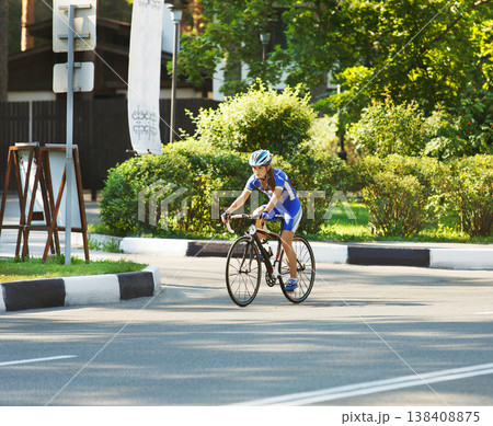 Female sportsman cyclist riding racing bicycle. Woman cycling on countryside summer sunny road or highway. Training for triathlon or cycling competition. 138408875