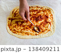 Top view of woman hands spreading organic tomato sauce on handmade pizza dough with spoon, traditional italian recipe preparation in cozy home kitchen, domestic culinary hobby lifestyle photography 138409211