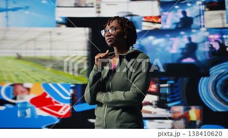 Woman receiving video recommendations delivered instantly on videowall. User enjoying digital era enabling unlimited streaming opportunities, looking at clips on digital interface, camera A Woman receiving video recommendations delivered instantly on videowall. User enjoying digital era enabling unlimited streaming opportunities, looking at clips on digital interface, camera A 138410620