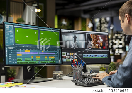 Professional editor working in video production with chroma key at agency office, doing color grading and creating a montage on dual monitors. Creative process with multimedia tech tools. 138410671