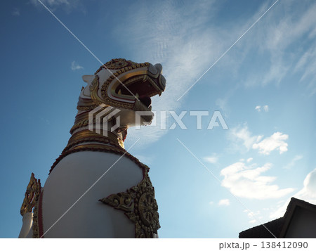 Mythical lion statue temple guardian golden ornament religious art blue sky cultural sculpture Majestic mythical lion statue 138412090