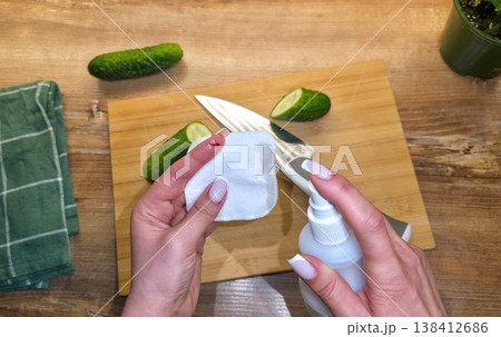 A woman is treating a knife cut on her finger in close-up against the background of a cutting board, cucumbers, and a knife in the kitchen. High quality photo 138412686