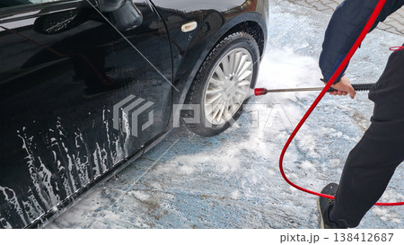 A young man is washing a black car at a touchless high-pressure car wash. High quality photo 138412687