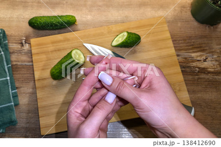 A close-up of a finger cut on the hand with a knife against the background of a cutting board, cucumbers, and a knife in the kitchen. High quality photo 138412690
